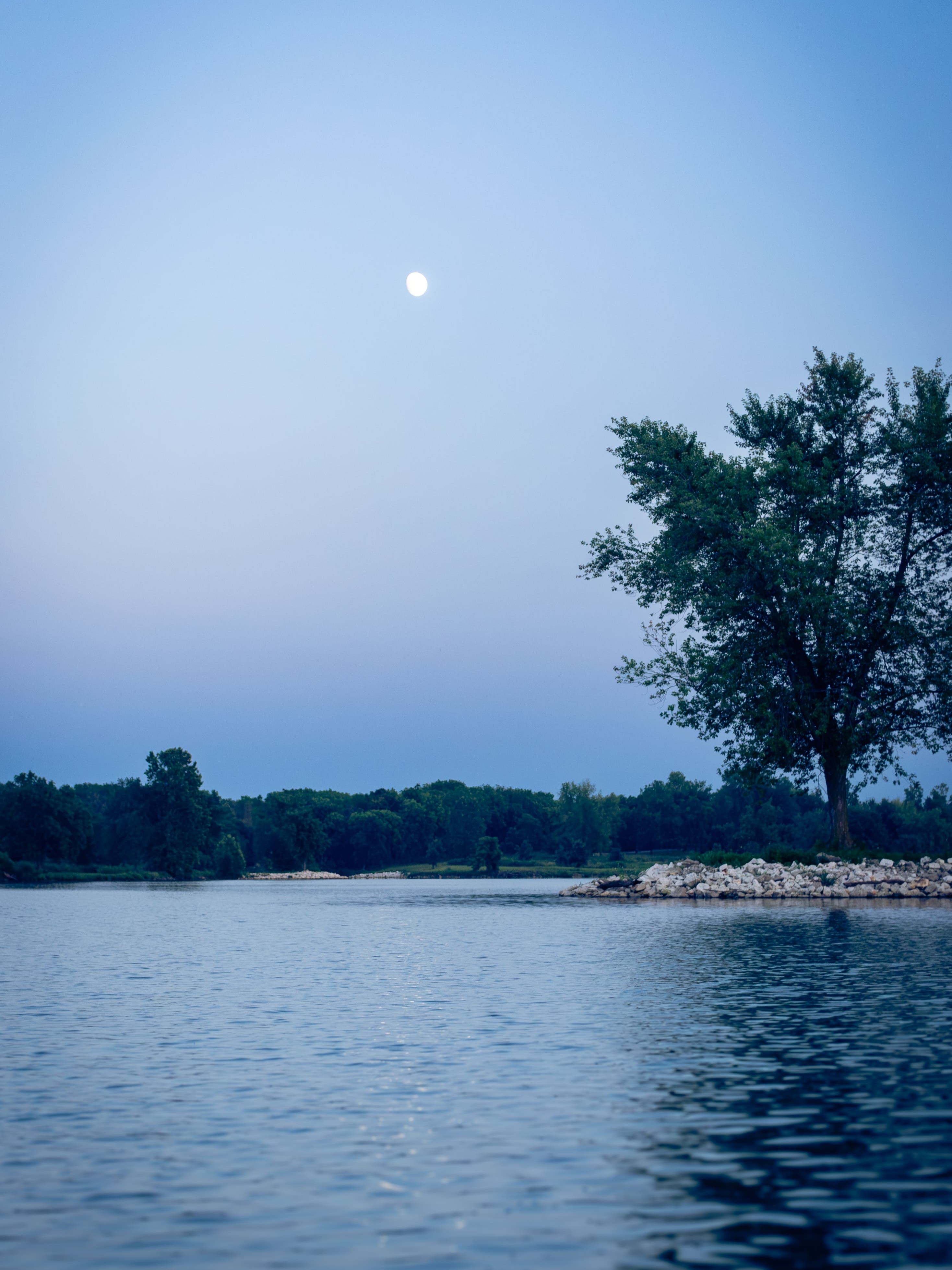 Moon shines over lake water at dusk